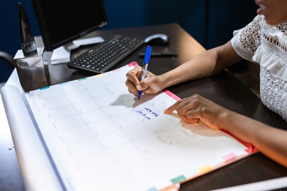 Person writing plans in a desk calendar