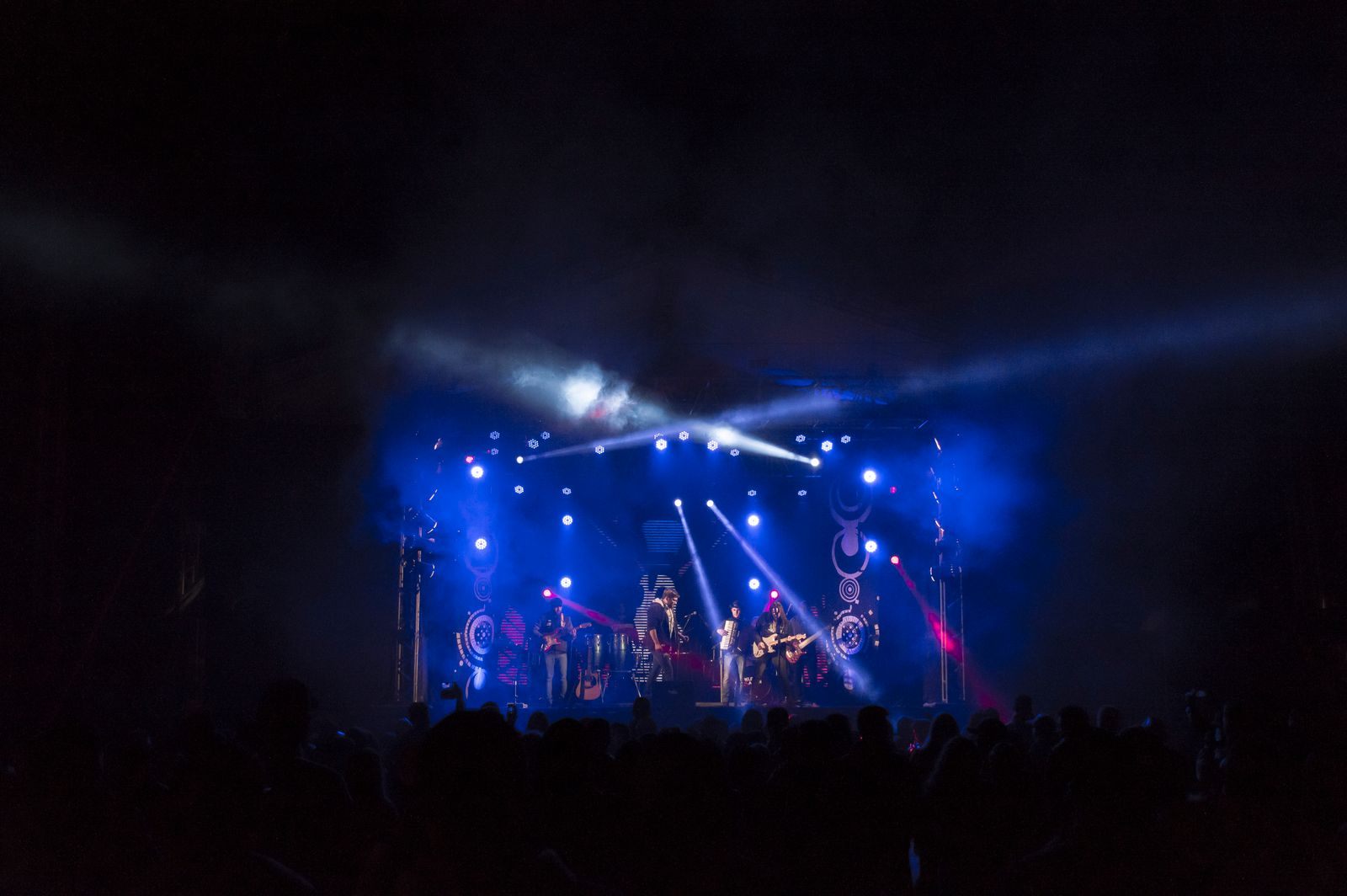 Rock band performing under colored stage lights for an energetic crowd